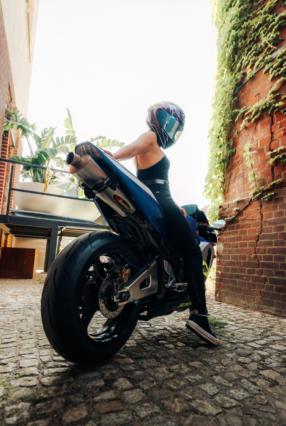 Riderin auf blauer Honda im Innenhof, Froschperspektive – Motorradfotografie